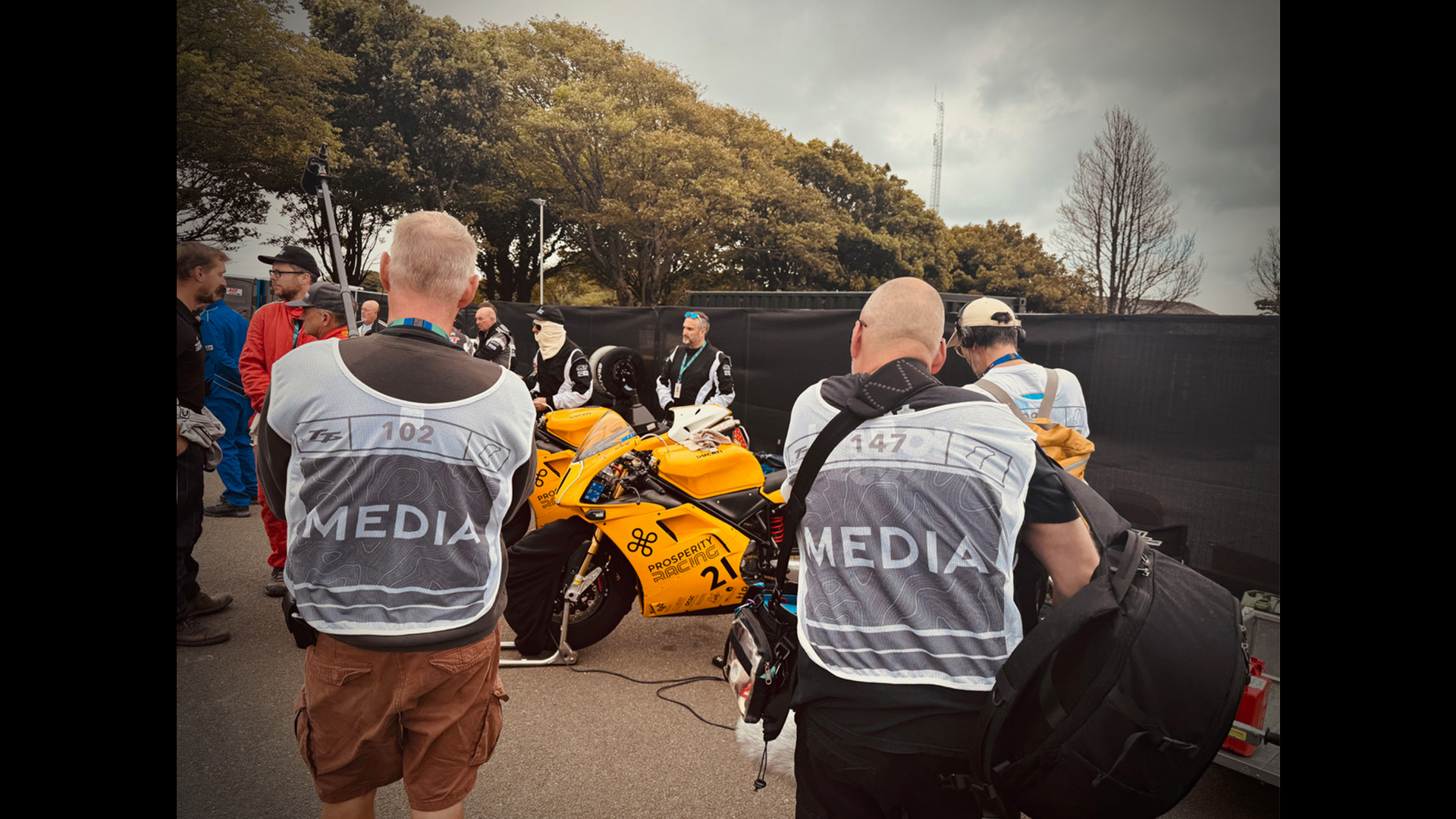 Media team photographing yellow motorbike featuring the Prosperity Wealth Logo