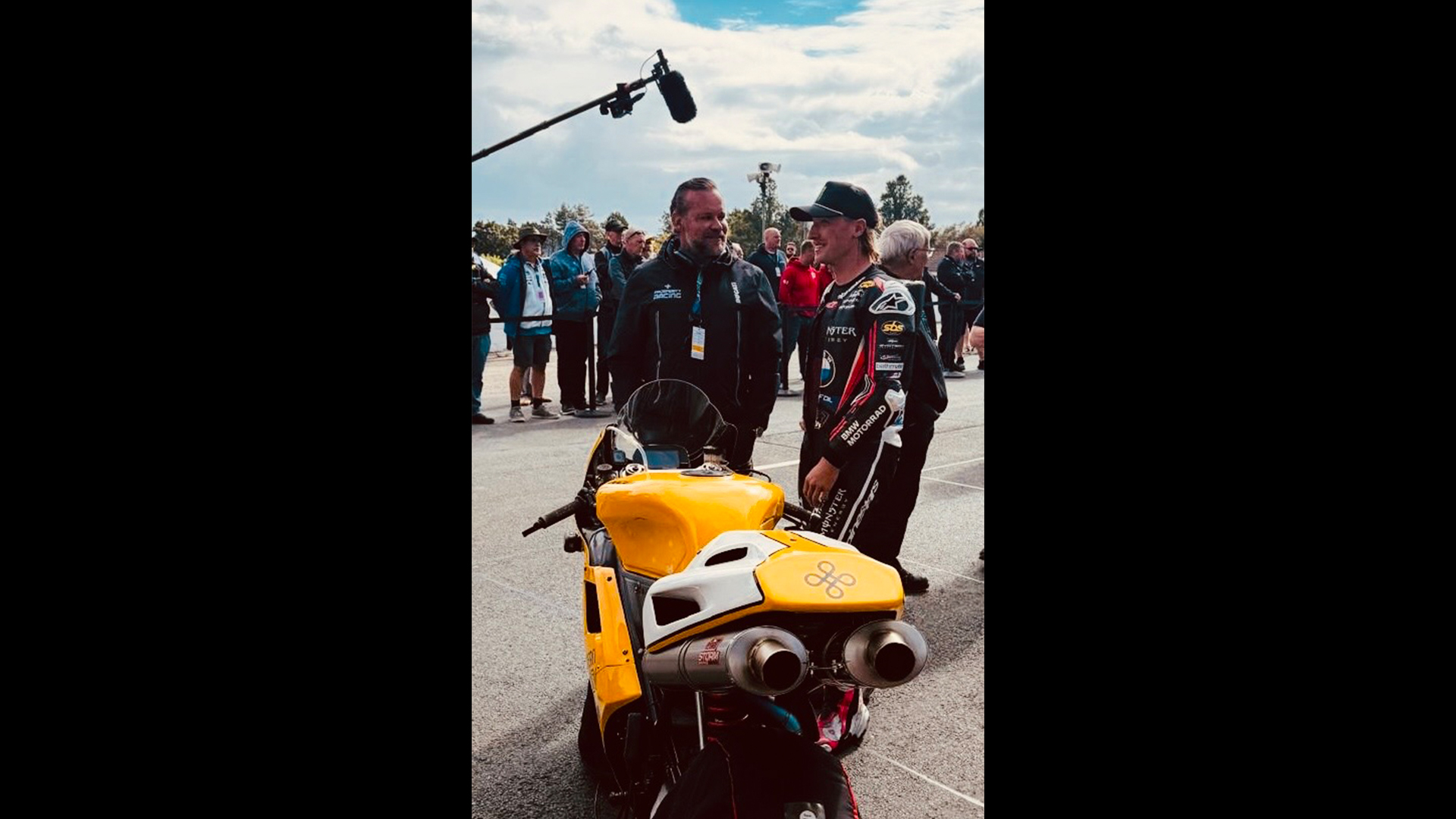 Motorbike rider being interviewed stood next to yellow motorbike